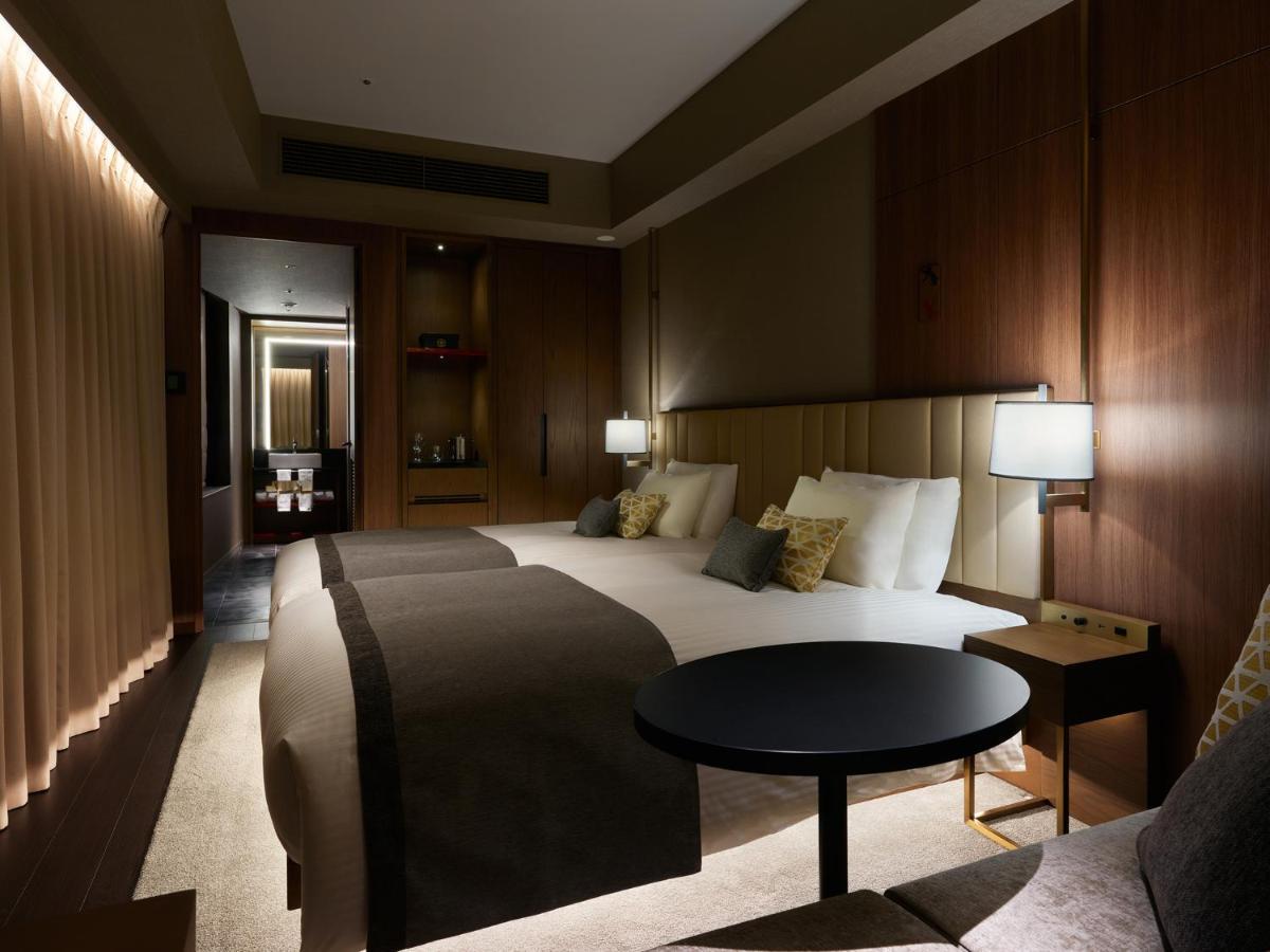 Mitsui Garden Hotel Roppongi Tokyo Premier Екстериор снимка The photo shows a stylish hotel room featuring two beds with plush bedding and decorative pillows. The walls are made of wood, creating a warm and modern atmosphere. There are bedside lamps on each side of the beds providing soft lighting. A small ro