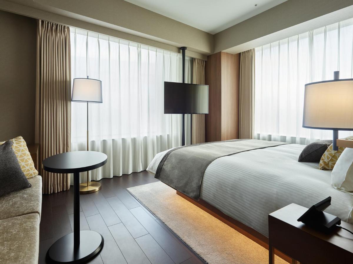 Mitsui Garden Hotel Roppongi Tokyo Premier Екстериор снимка The photo shows a modern hotel room with a contemporary design. It features a large bed with crisp white linens, sitting against a wall with floor-to-ceiling windows covered by sheer curtains, allowing natural light to filter in. To the side, there's