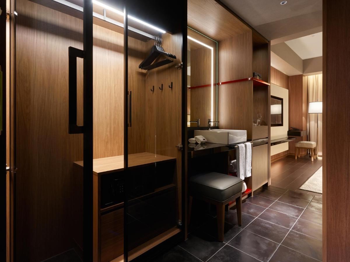 Mitsui Garden Hotel Roppongi Tokyo Premier Екстериор снимка The photo depicts a modern and stylish hotel room's closet area. It features wooden cabinetry with a sleek finish, including mirrored doors. Inside, there are hangers for clothing and hooks mounted on the wall. A small bench or chair is positioned ne