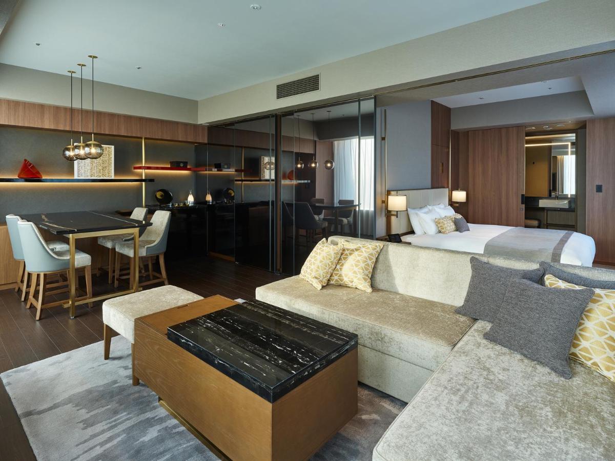Mitsui Garden Hotel Roppongi Tokyo Premier Екстериор снимка The image shows a modern hotel room or suite that features a contemporary design. Key elements include:

- A comfortable seating area with a light-colored sofa and a stylish coffee table.
- A dining area with a table and chairs, suggesting space for 