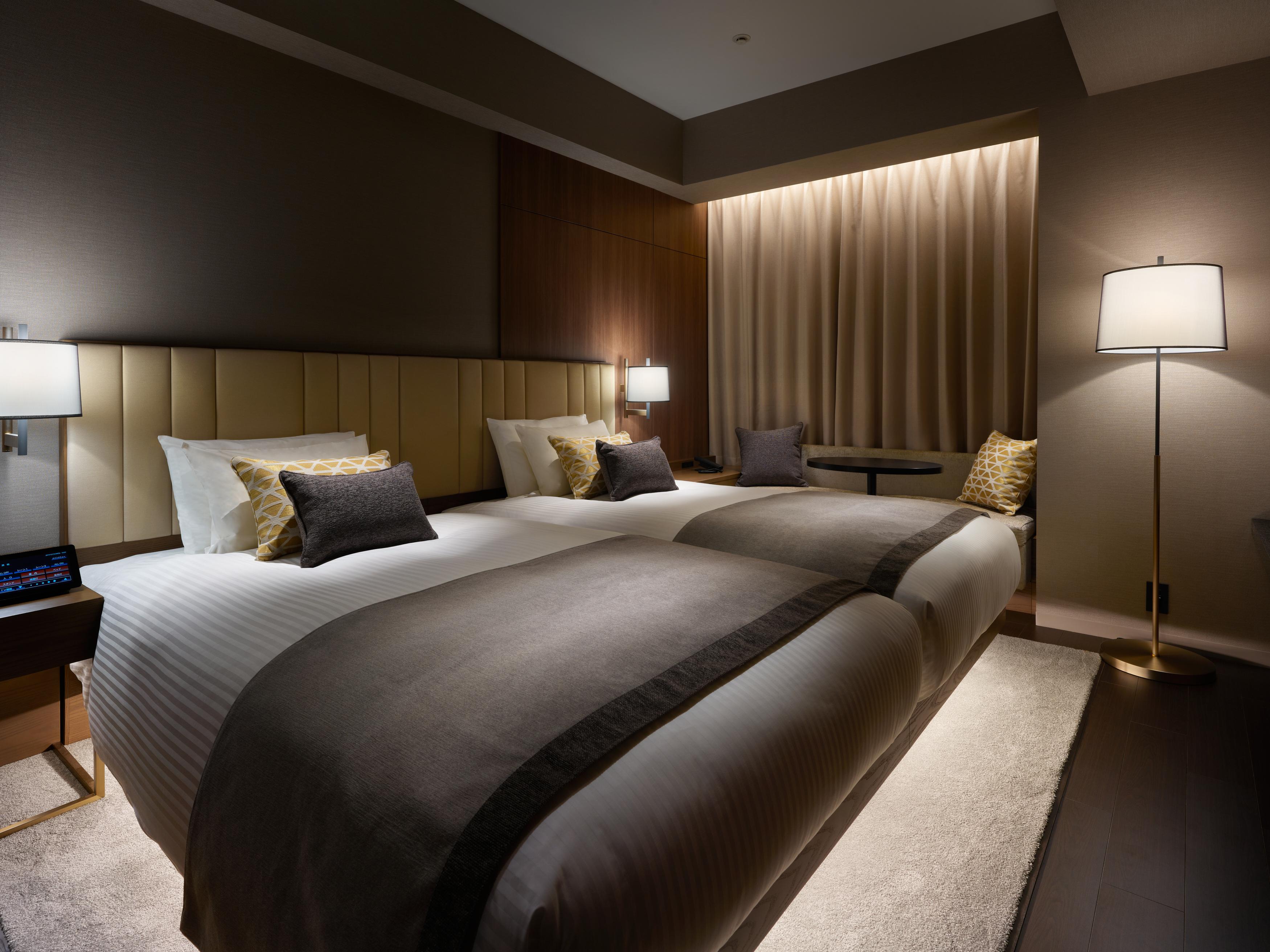 Mitsui Garden Hotel Roppongi Tokyo Premier Екстериор снимка The photo shows a modern hotel room featuring two beds with elegant bedding in neutral colors. Each bed is adorned with decorative pillows. The room has a sophisticated ambiance with dim lighting, highlighted by table lamps on either side of the beds