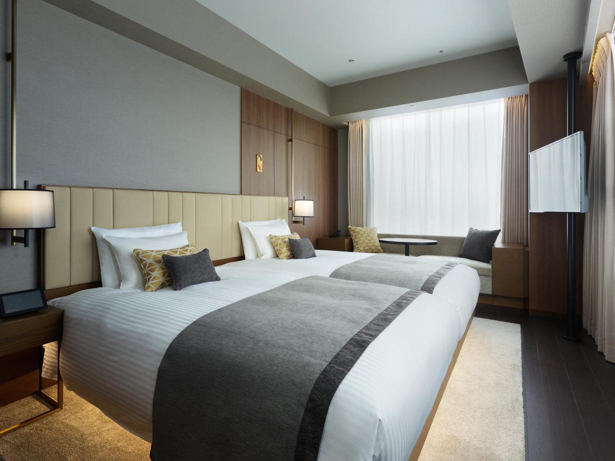 Mitsui Garden Hotel Roppongi Tokyo Premier Екстериор снимка The photo shows a modern hotel room featuring two beds with white linens and decorative pillows. The room has a minimalist design, with neutral-colored walls and wooden accents. Natural light comes in through large windows, which are partially covere