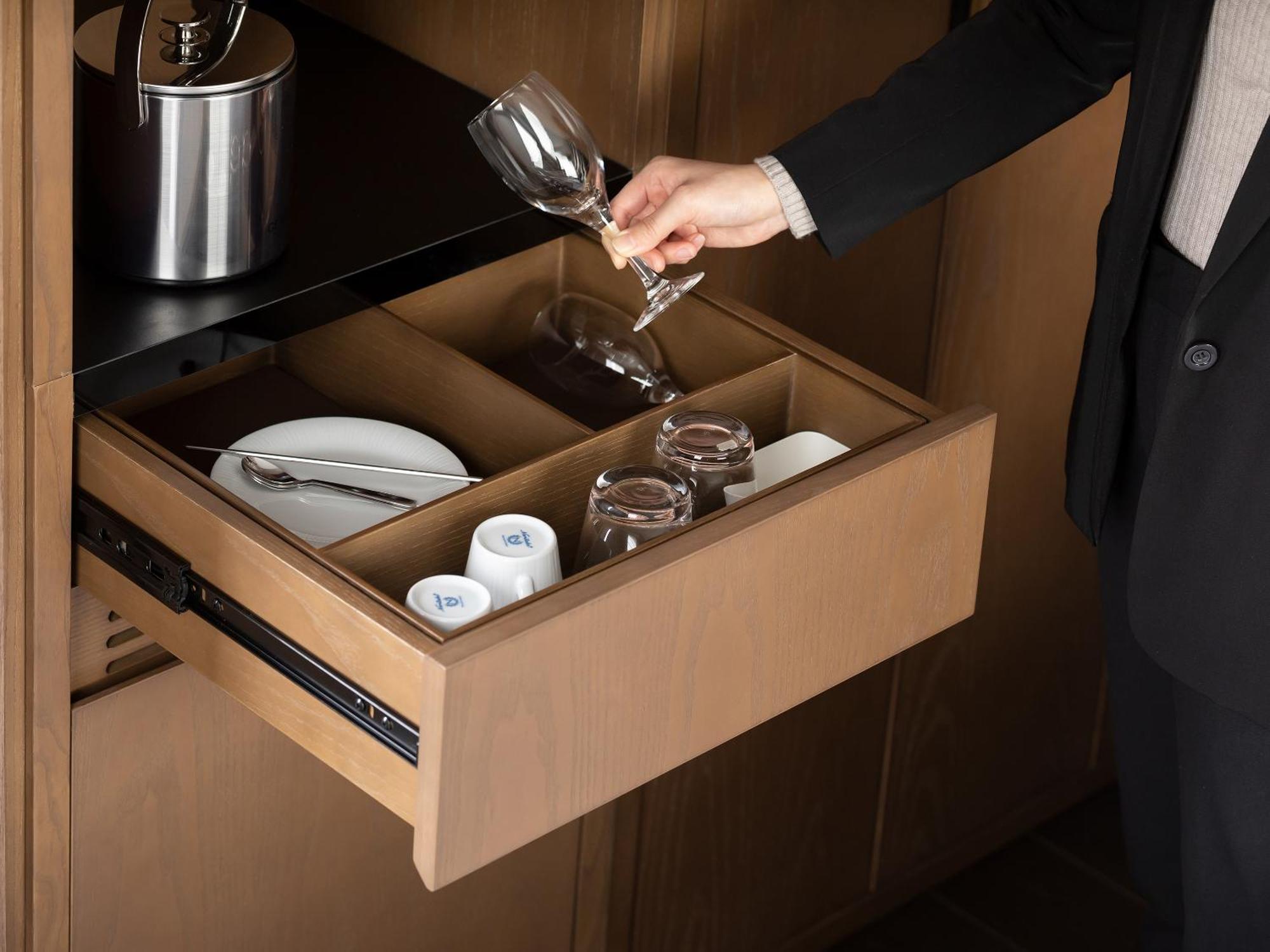 Mitsui Garden Hotel Roppongi Tokyo Premier Екстериор снимка The photo depicts a wooden kitchen drawer being pulled open, revealing a neatly organized selection of dishware. Inside, there are glass cups, a wine glass being held by a person, and plates. The setting appears modern and sleek, with a sophisticated